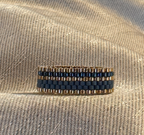 Ein goldener Ring mit blauen und goldenen Perlen in Streifenmuster.