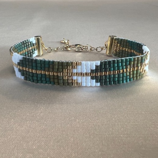 Armband aus grünen, weißen und goldenen Perlen in geometrischem Muster.